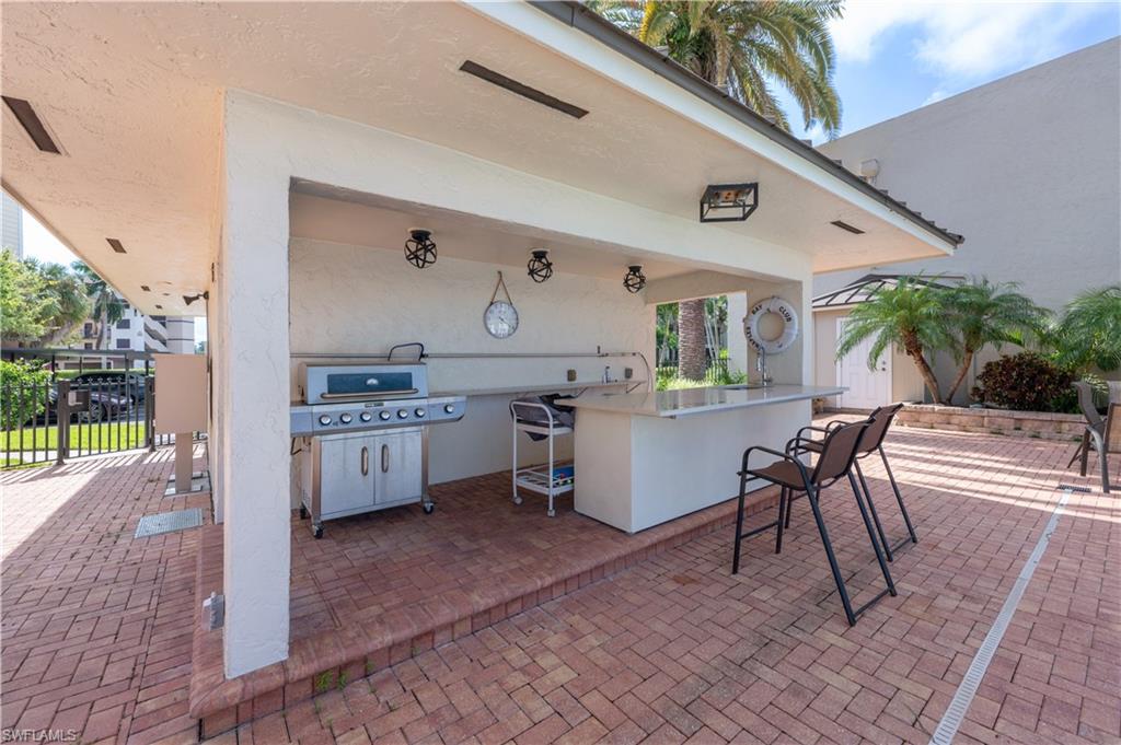 800 River Point Drive, Unit 207 Naples, FL 34102 - Photo 43 of 47 a white kitchen with a sink a stove a table and chairs