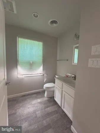 a bathroom with a toilet sink a vanity and windows