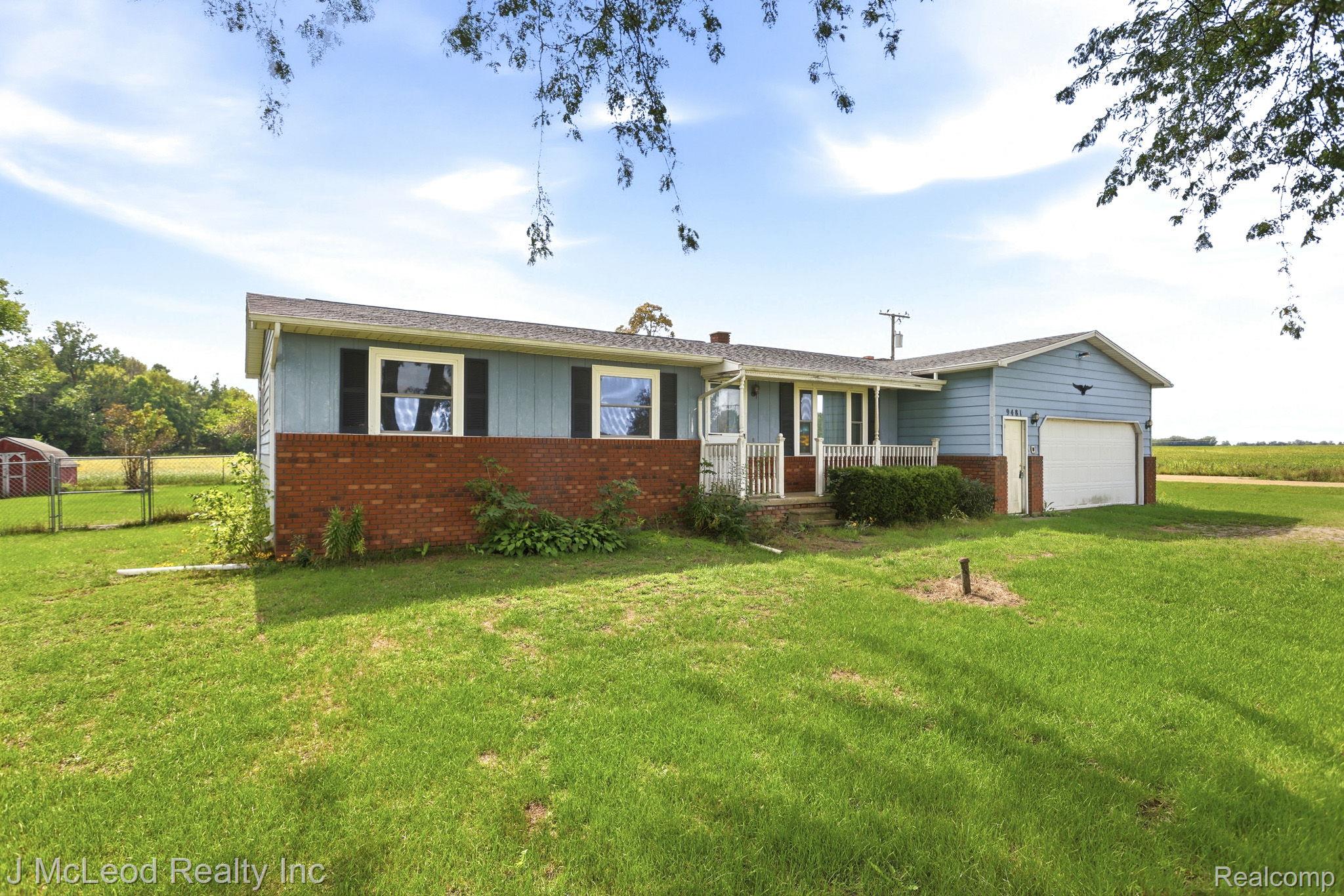 9481 Swaffer Road Vassar, MI 48768 - Photo 1 of 39 Exterior featuring brick and siding construction, covered front porch, attached garage, and a expansive lawn