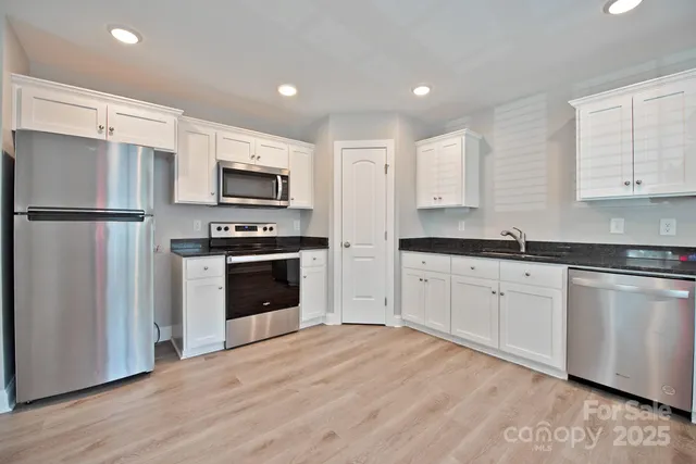 a kitchen with granite countertop a refrigerator stove and microwave