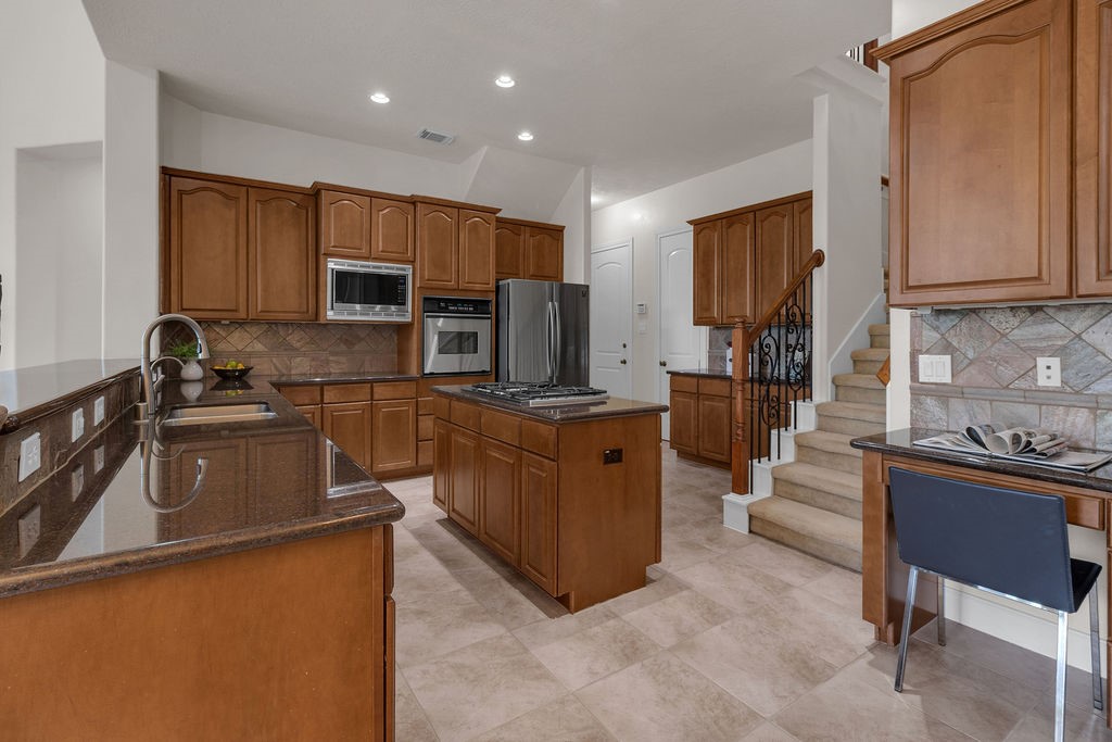 7306 Starflower Katy, TX 77494 - Photo 20 of 50 a kitchen with kitchen island granite countertop a sink counter top space appliances and cabinets