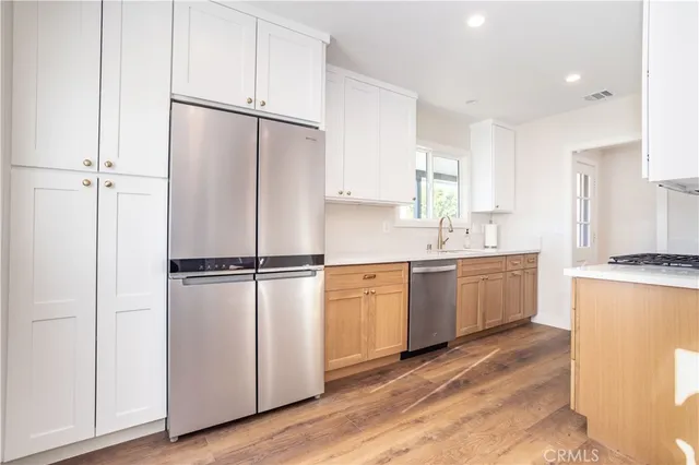 a kitchen with a refrigerator a sink and white cabinets