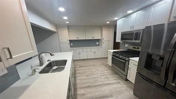 a kitchen with granite countertop a refrigerator and a stove top oven