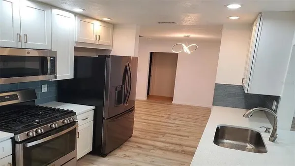 a kitchen with stainless steel appliances granite countertop a refrigerator and a stove top oven