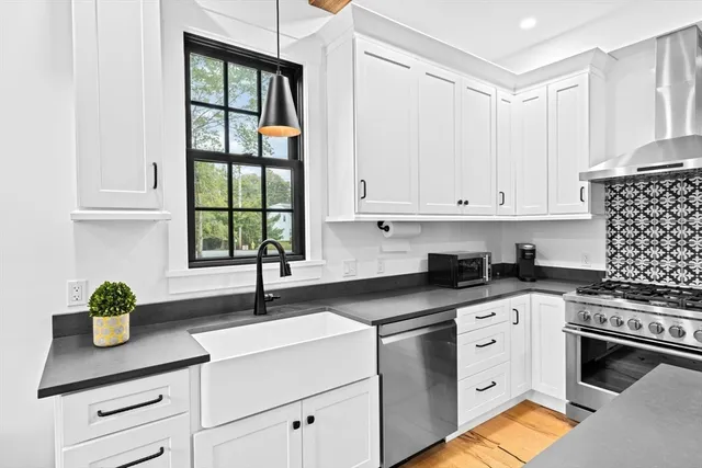 a kitchen with granite countertop a sink cabinets stainless steel appliances and a window