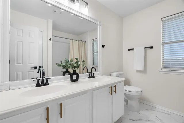 a bathroom with a sink a toilet and a large mirror