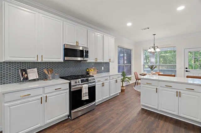 a kitchen with a white cabinets and wooden floor