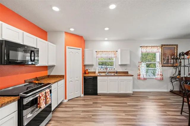 a kitchen with stainless steel appliances a stove a sink a refrigerator cabinets and a dining table with wooden floor