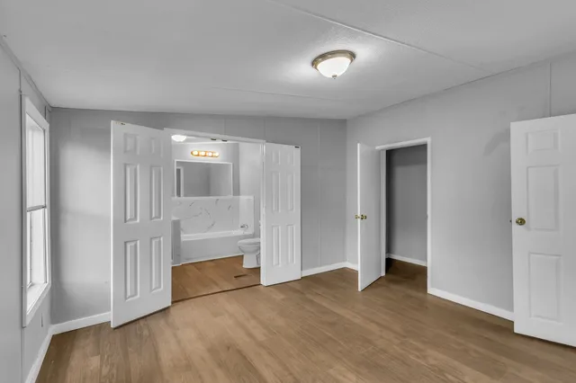 an empty room with wooden floor and windows