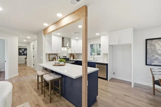 a kitchen with a dining table chairs wooden floor appliances and cabinets