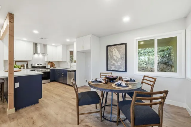 a kitchen with a dining table chairs and large windows