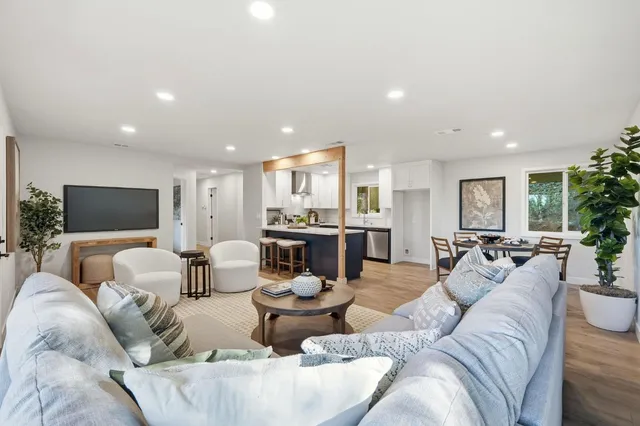 a living room with furniture kitchen view and a large window