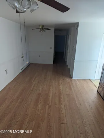 a view of a room with wooden floor and a ceiling fan