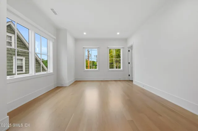 a view of an empty room with a window and wooden floor