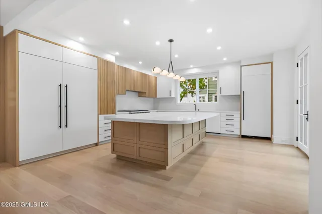 a large white kitchen with a large window and stainless steel appliances