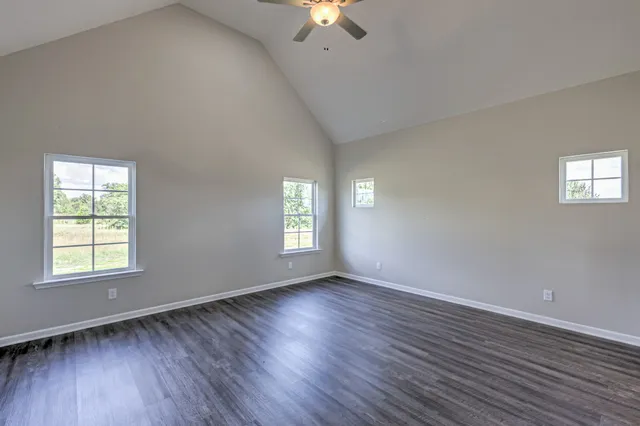 an empty room with wooden floor chandelier fan and windows