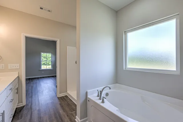 a view of a hallway with wooden floor and a bathroom