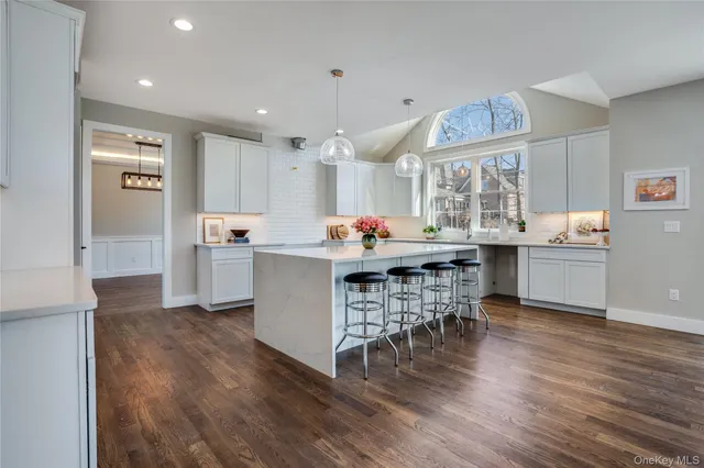 a room with stainless steel appliances kitchen island granite countertop a sink cabinets and wooden floor