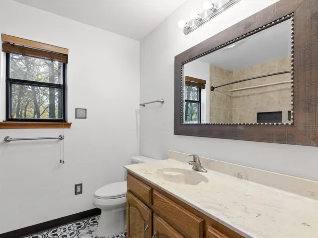 a bathroom with a granite countertop sink vanity mirror and toilet