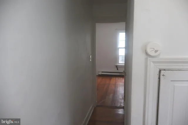 a view of a hallway with wooden floor and a bathroom