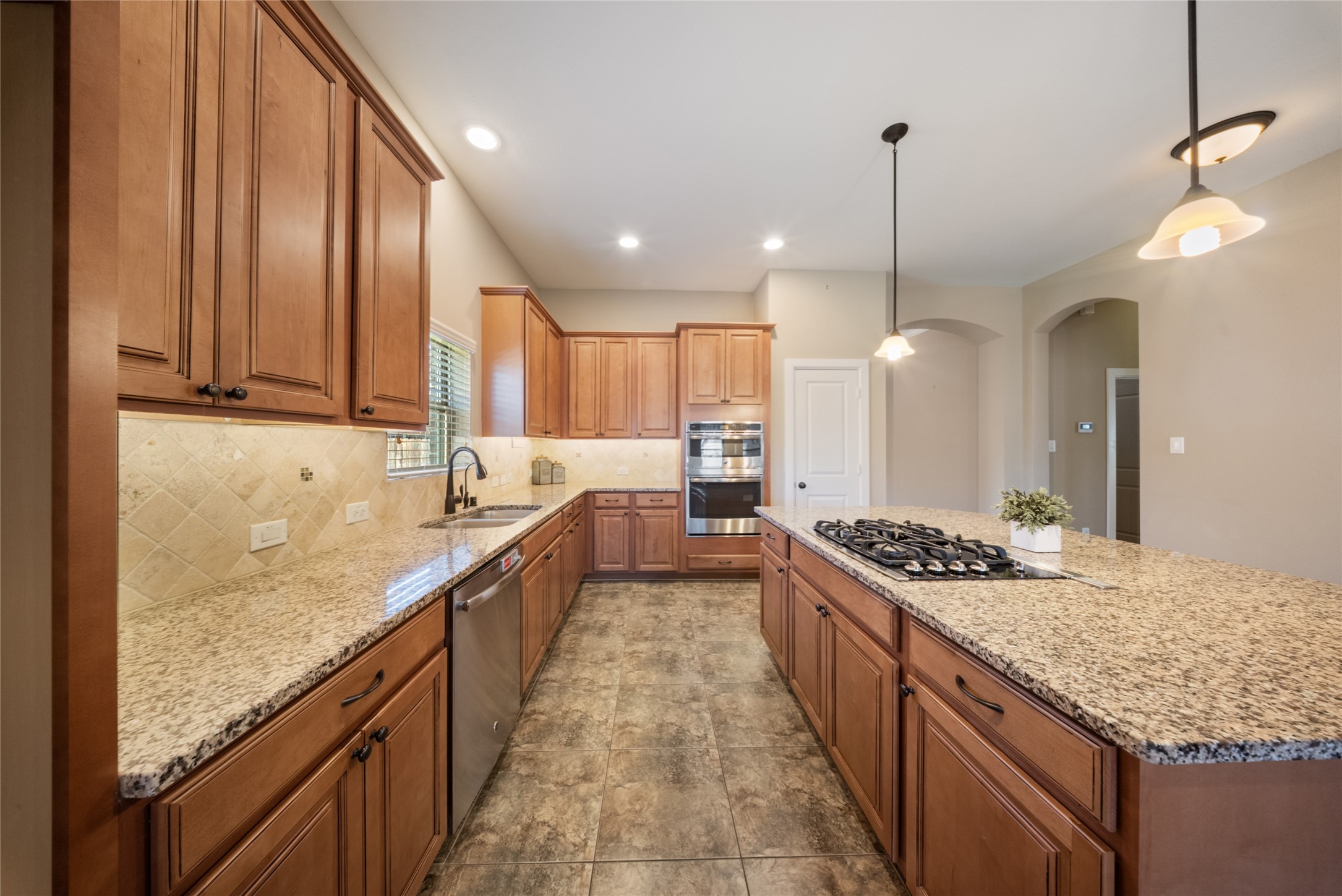 176 Castlegate Lane Houston, TX 77065 - Photo 8 of 33 a large kitchen with kitchen island granite countertop a sink a stove and a wooden floors