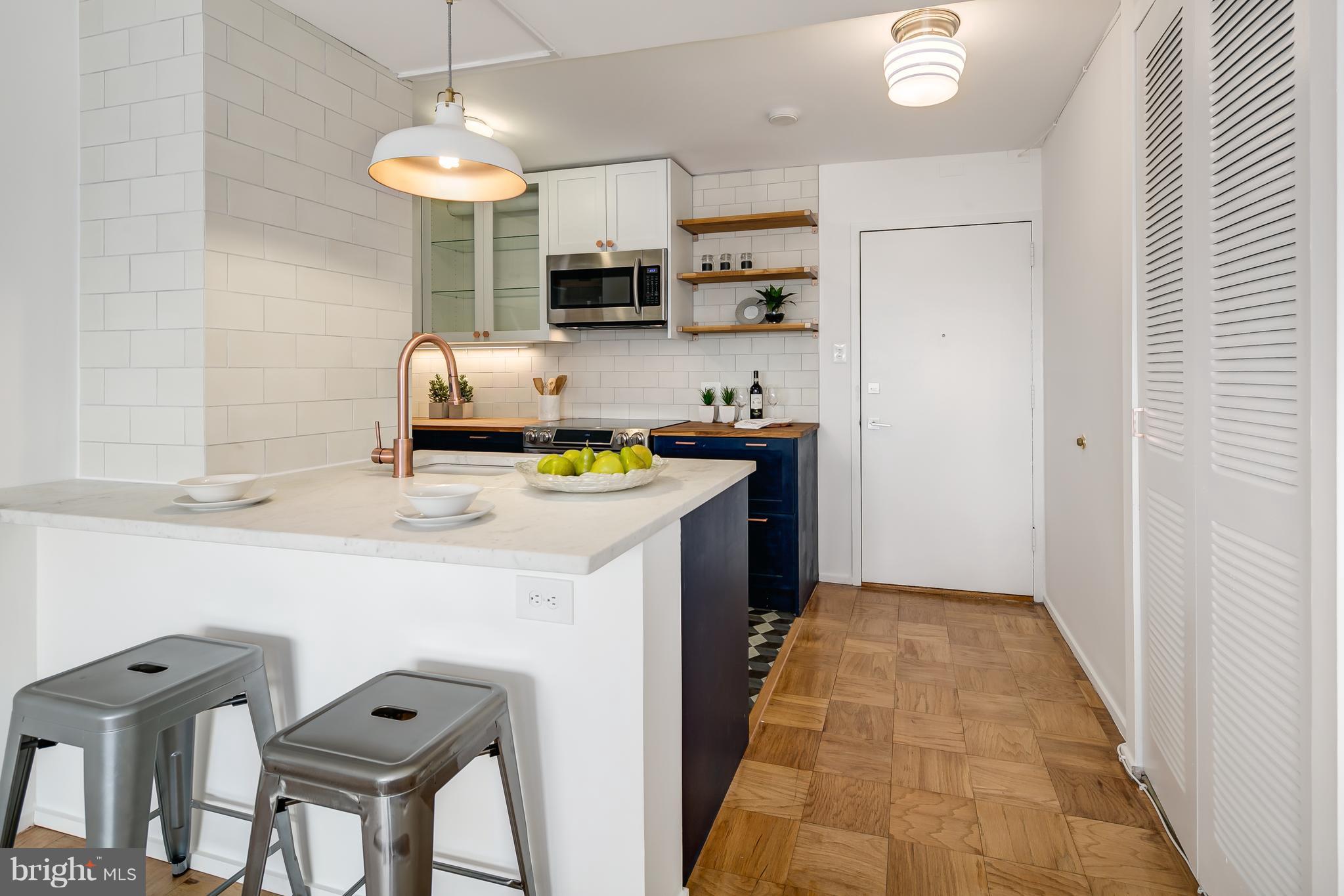 1301 Delaware Avenue Southwest, Unit N512 Washington, DC 20024 - Photo 4 of 28 a kitchen with stainless steel appliances a sink a stove a refrigerator a microwave oven with white cabinets and wooden floor