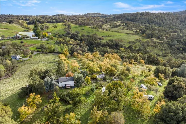 a backyard of a house with large trees and wooden fence
