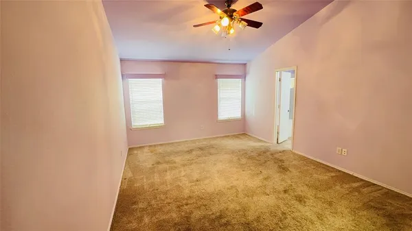 a view of an empty room and chandelier fan