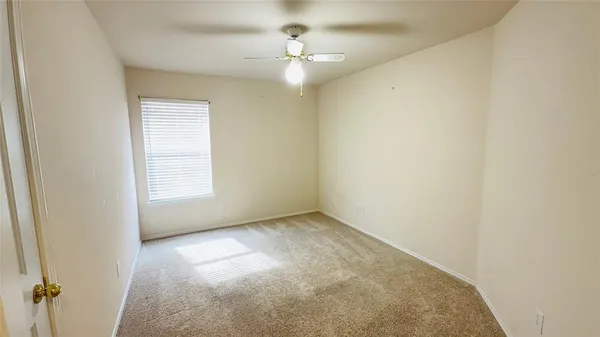 an empty room with a chandelier fan and windows