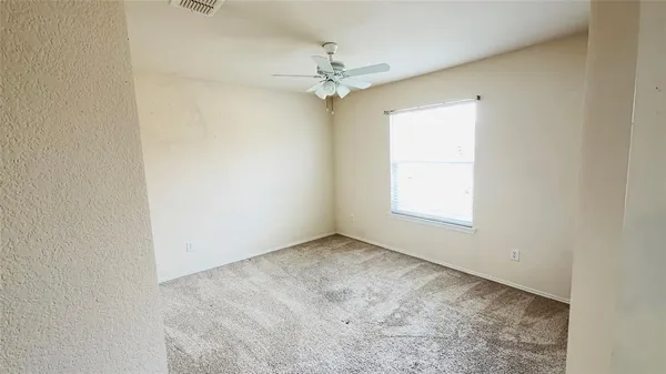 an empty room with a window and a fan