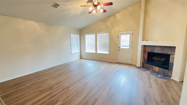 an empty room with wooden floor fireplace and windows