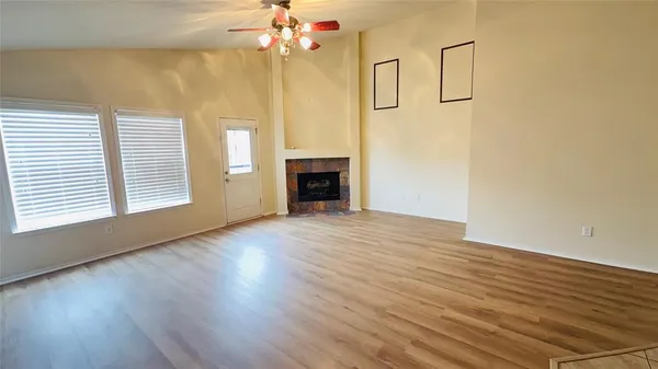 an empty room with wooden floor fireplace and windows