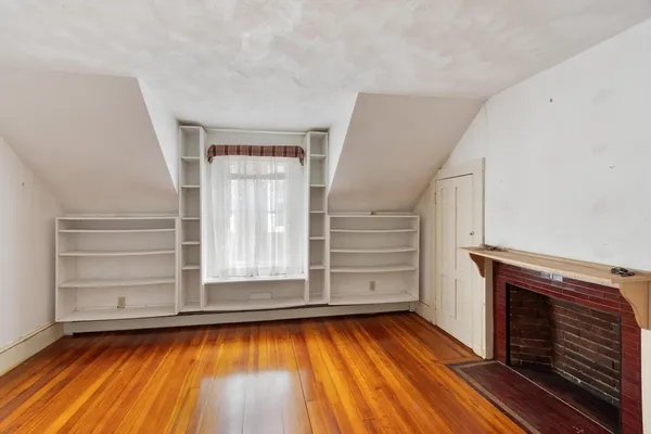 a view of empty room with wooden floor and fireplace