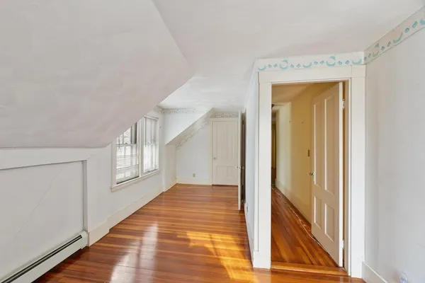 a view of a hallway with wooden floor and cabinet