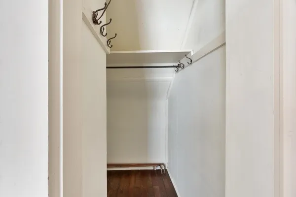 a view of an empty walk in closet with wooden floor