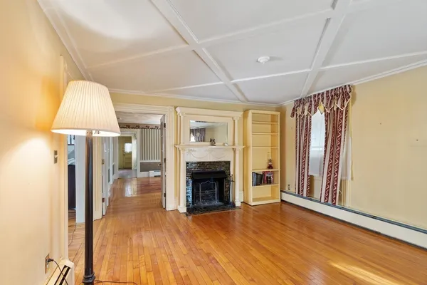 a view of an empty room with wooden floor fireplace and a window