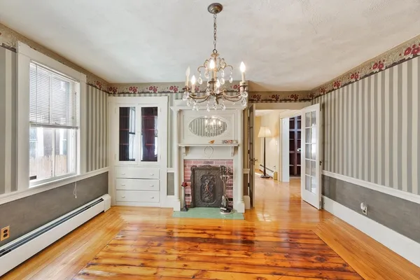 a view of a big room with wooden floor fireplace and windows