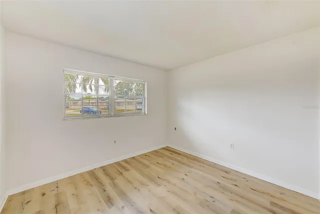 an empty room with wooden floor and window