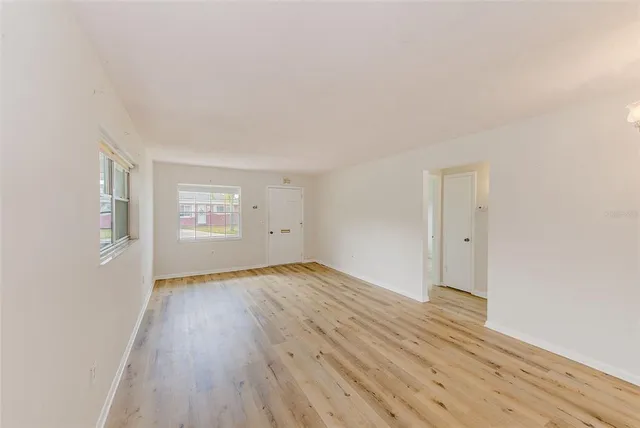 a view of an empty room with wooden floor and a window