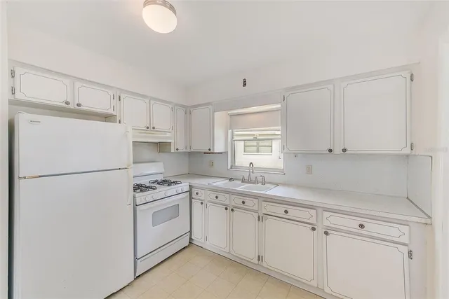 a kitchen with cabinets appliances a sink and a window