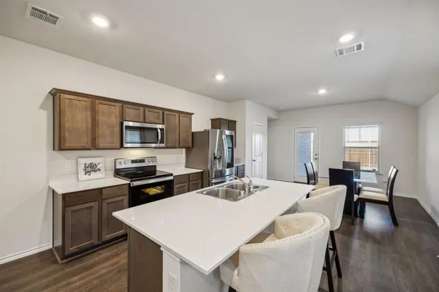 a large kitchen with a table chairs refrigerator and microwave