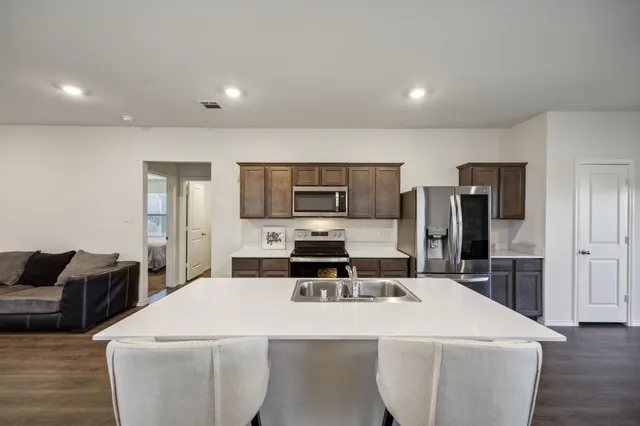 a kitchen with stainless steel appliances a stove a sink a refrigerator and cabinets