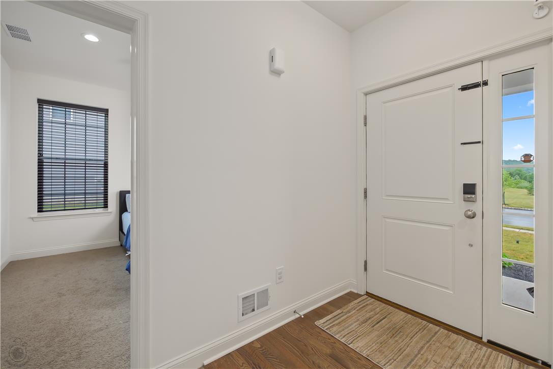 A welcoming entry features gleaming wood flooring and a secure entry door with an adjacent window.