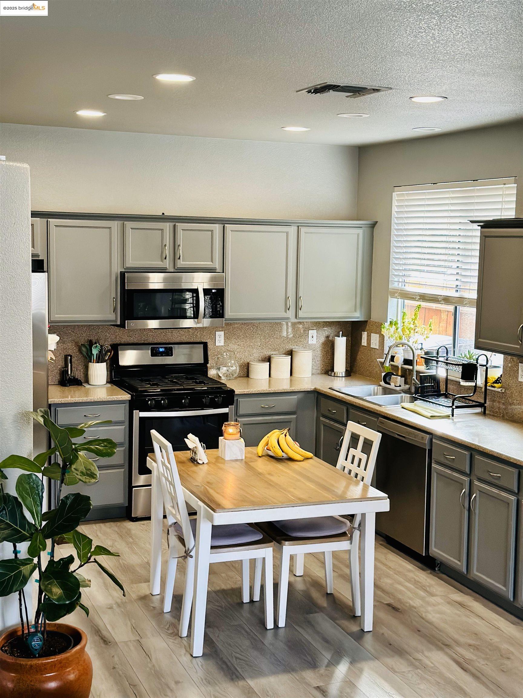 4519 Twin Creeks Court Tracy, CA 95377 - Photo 3 of 34 a kitchen with a table chairs microwave and cabinets
