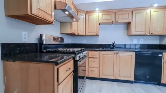 a kitchen with stainless steel appliances granite countertop a sink and a stove