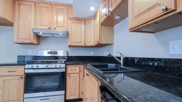 a kitchen with granite countertop a stove sink and cabinets