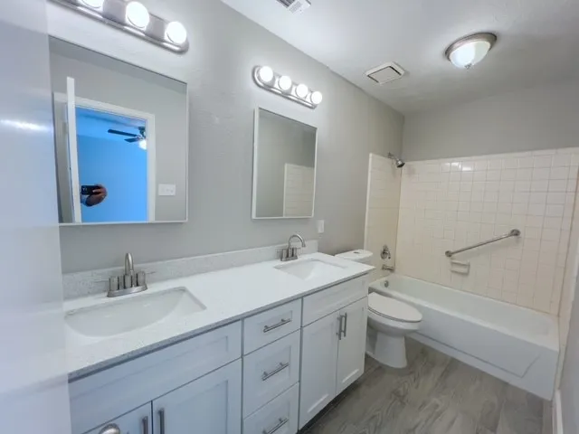 a bathroom with a double vanity sink a toilet and a large mirror