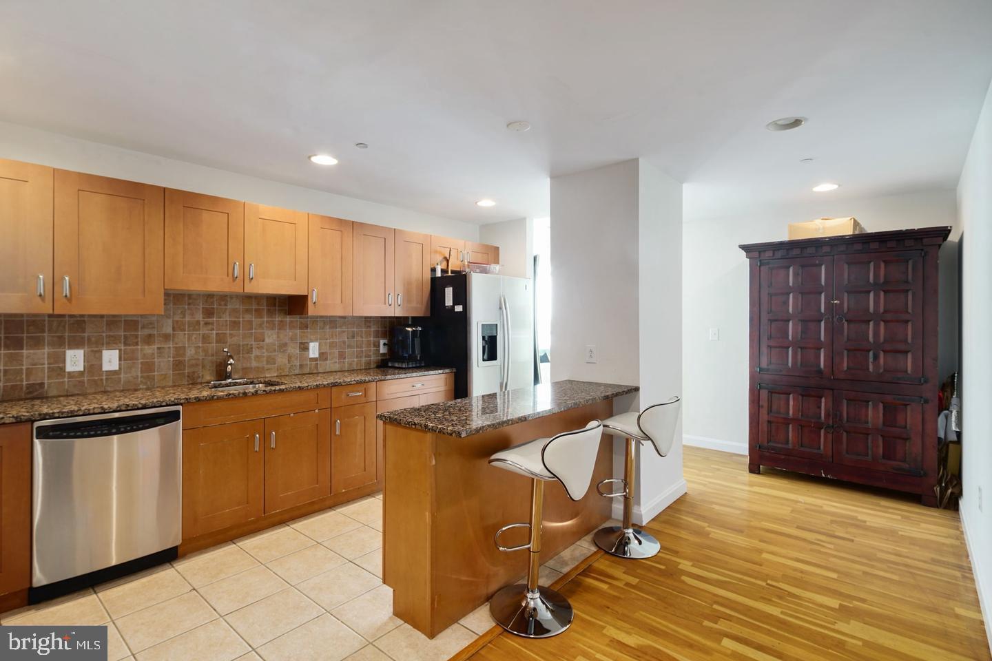 901 North Penn Street, Unit R1501 Philadelphia, PA 19123 - Photo 8 of 25 a kitchen with granite countertop a refrigerator and wooden cabinets