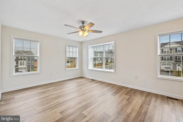 a view of an empty room with a window and wooden floor