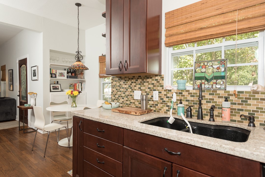 2805 Lafayette Avenue Austin, TX 78722 - Photo 11 of 23 Kitchen featuring a sink, backsplash, dark wood finished floors, and light stone counters